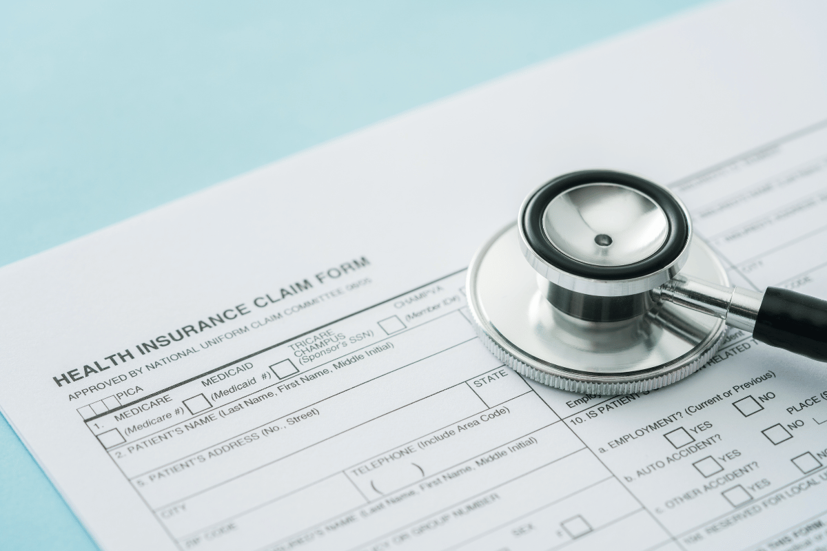 Stethoscope placed on top of a health insurance claim form, representing clinical trial and claims process.