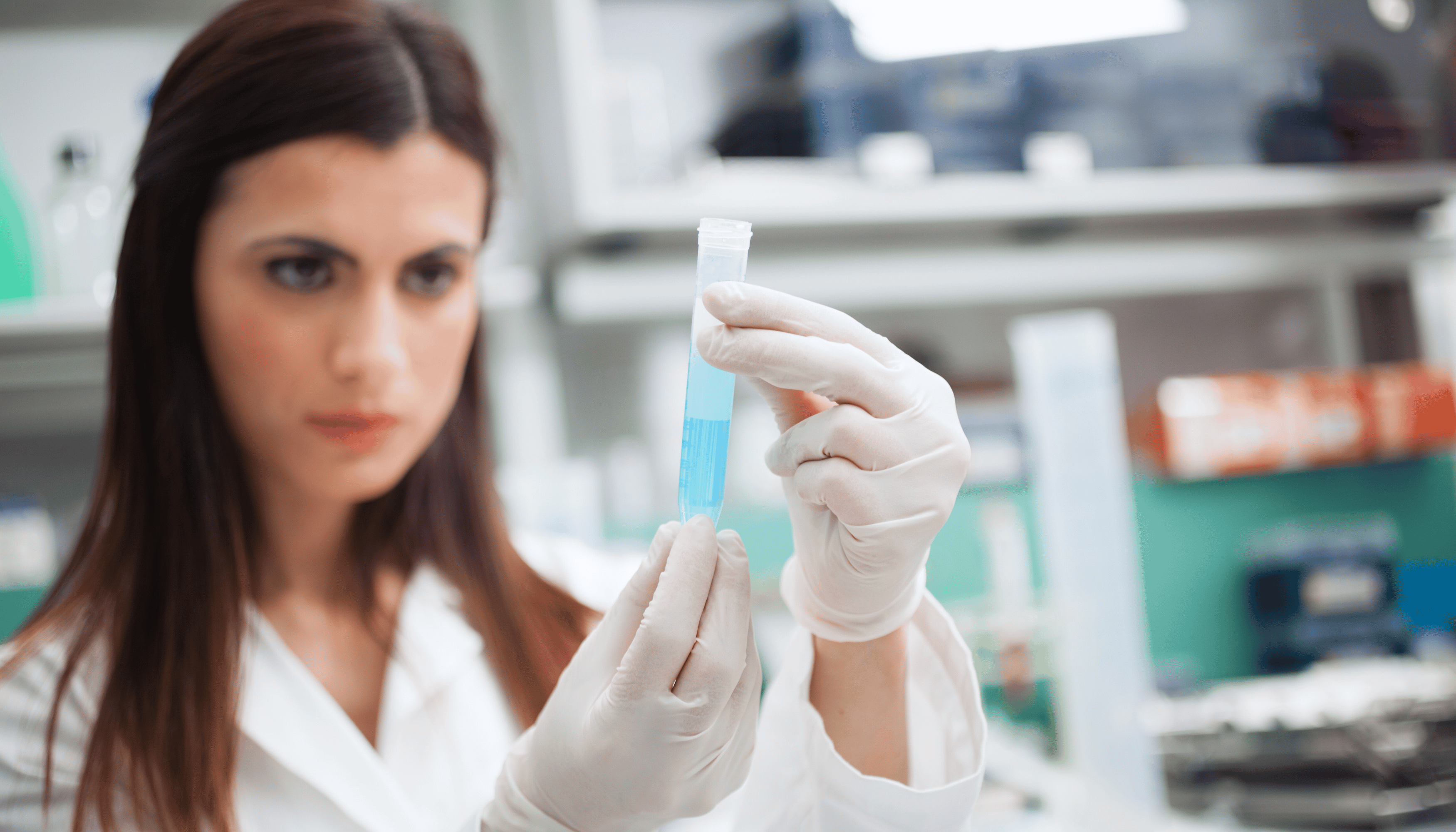 Scientist in a laboratory holding a test tube filled with a blue liquid, focused on analyzing the substance during clinical trials.