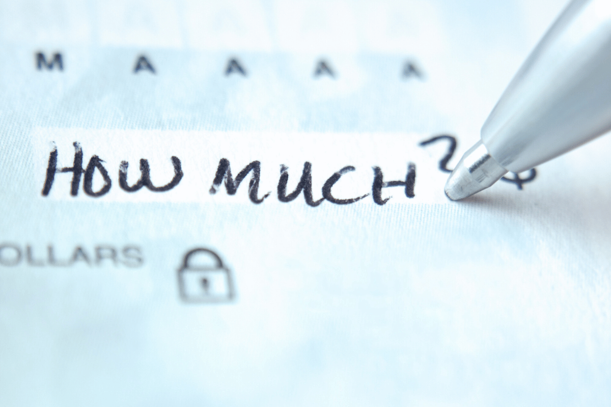 Close-up of a pen writing 'How Much?' on a financial document, symbolizing a question about costs or financial considerations.