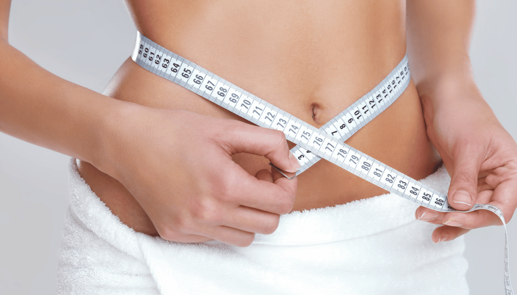 Close-up of a person measuring their waist with a tape measure, symbolizing weight loss or fitness progress.