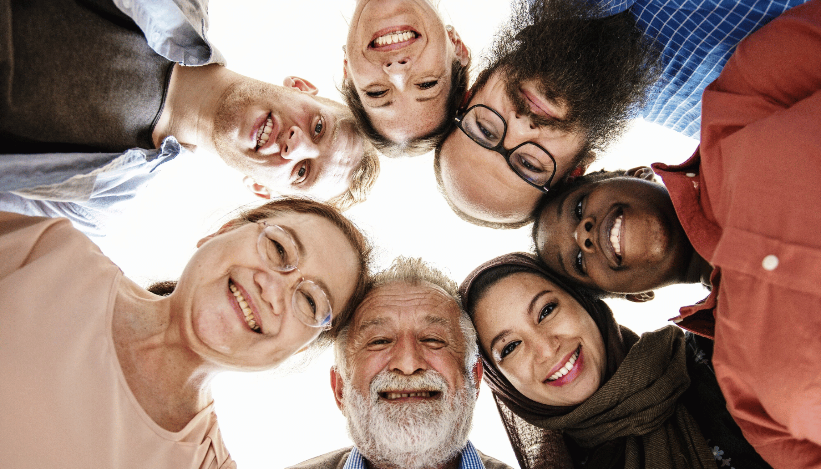 Smiling and diverse group of people standing in a circle, symbolizing inclusion and unity.